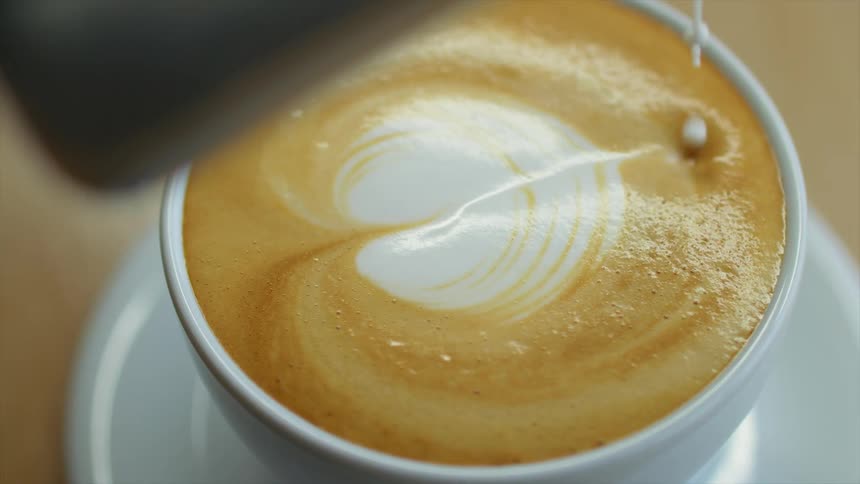 Cream is poured on a drink in a mug