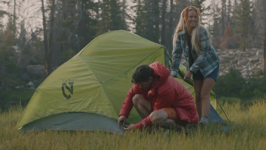 A man and woman are setting up a tent together