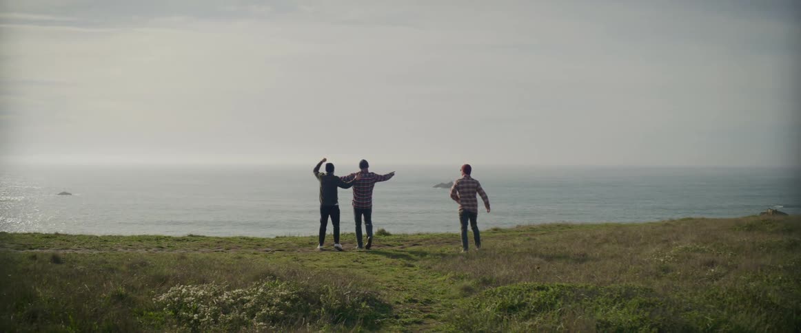 Three men walk near the shore together