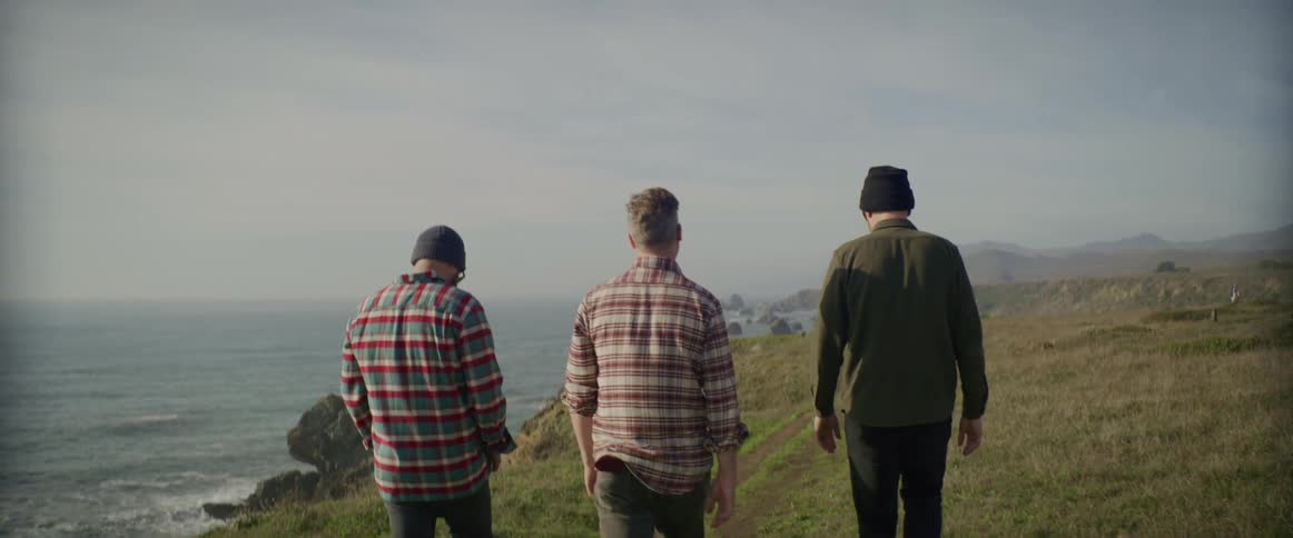 Male friends walking along a trail overlooking the coast