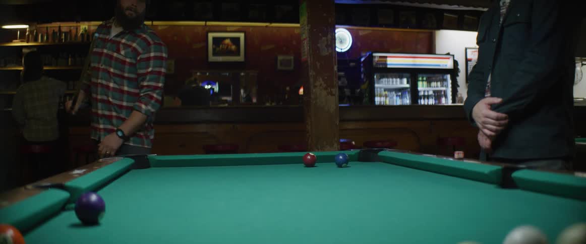 Man hitting a pool ball with a cue stick on a billiard table inside a restaurant