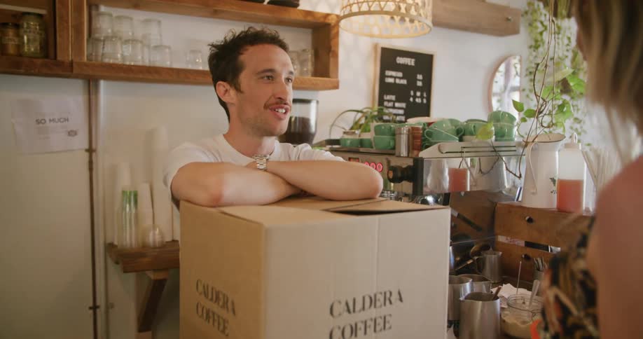 A woman brings a box to a cafe employee and they talk happily