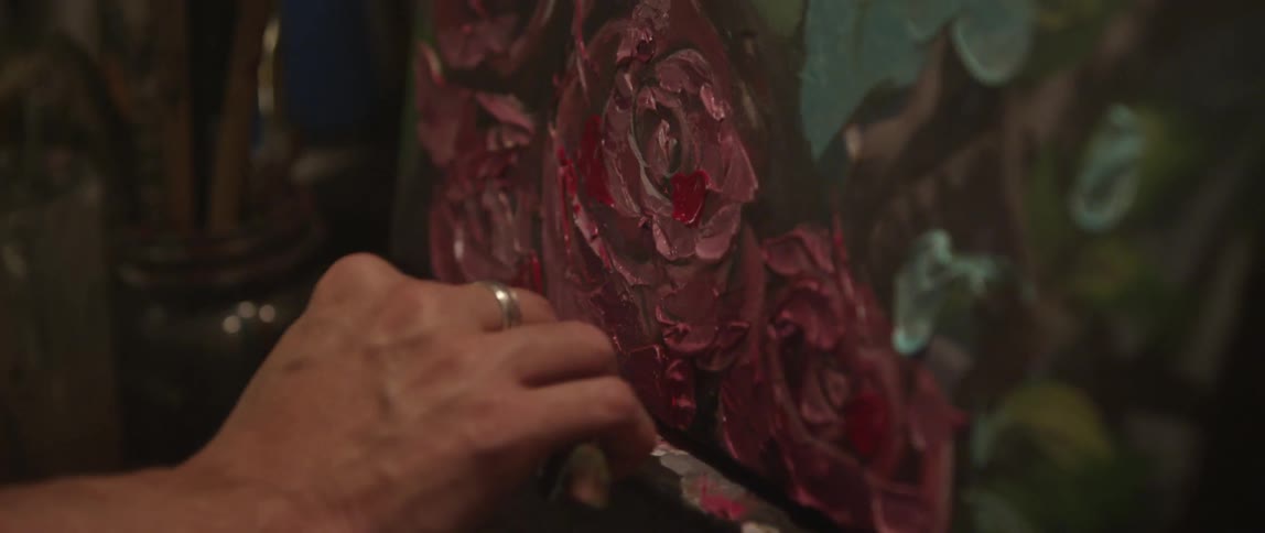 A person is painting a portrait with flowers