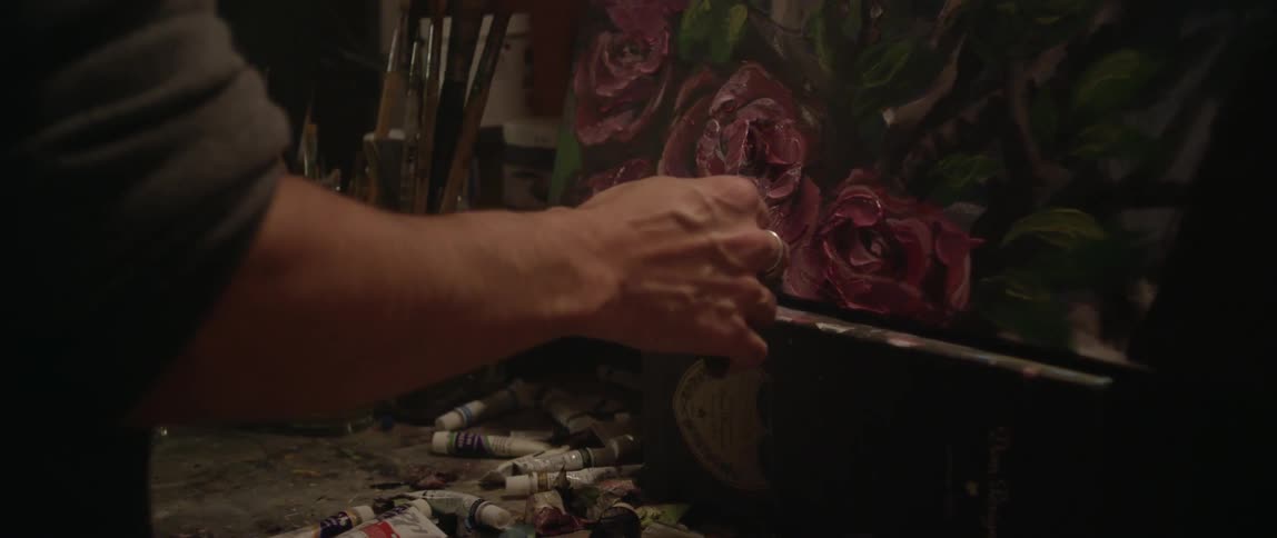 A person is painting red flowers