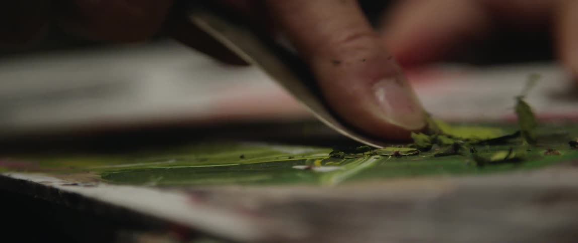 A person is scraping paint on his easel