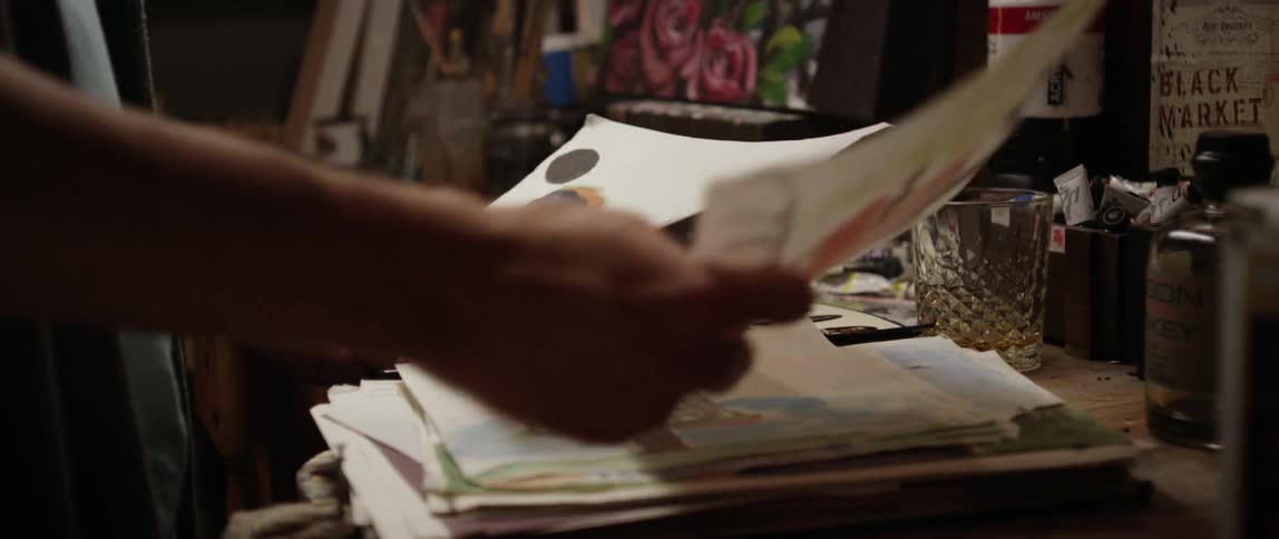 A person examines artwork on various papers