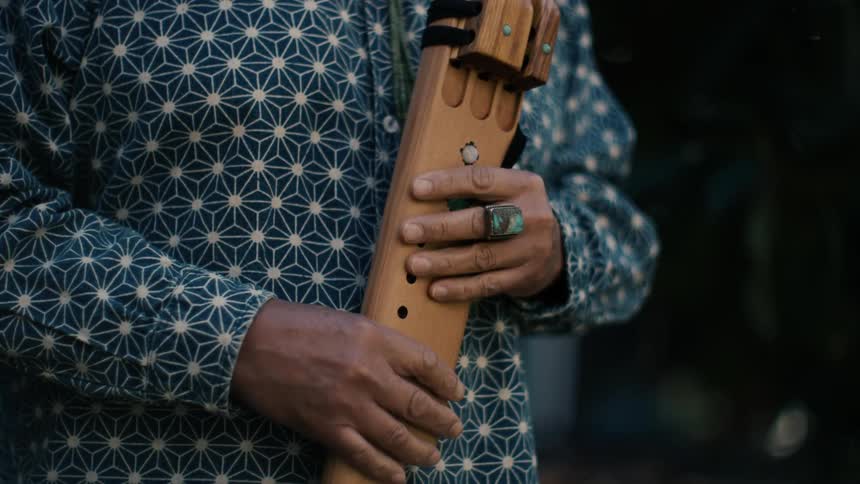 Man holds wooden wood wind decorated with semi precious gems