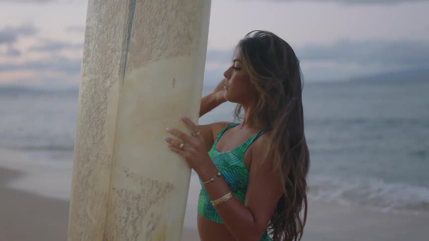 A woman in a bathing suit is holding up a surboard