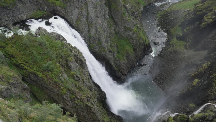 Mist rising from the bottom of a canyon under a waterfall in the mountains