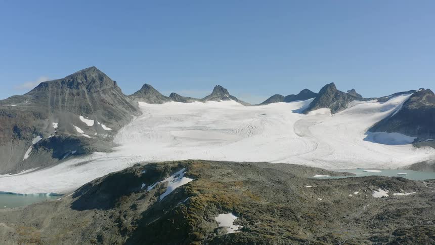 Ice fills valley near lake under clear sky