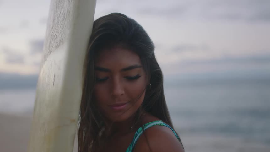 A woman is posing for the camera while standing at the beach