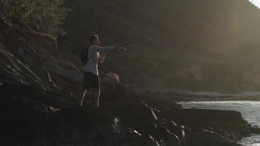 A man is fishing on the coast at dusk in spring