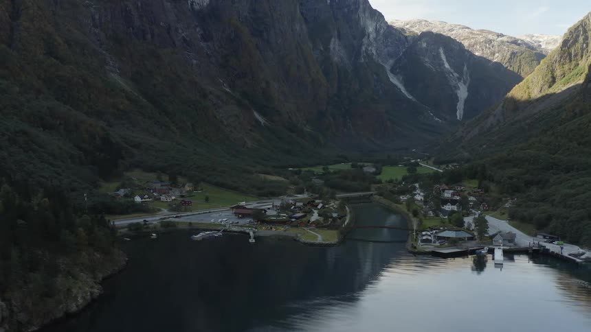 A valley nestled in the mountains with a river and buildings