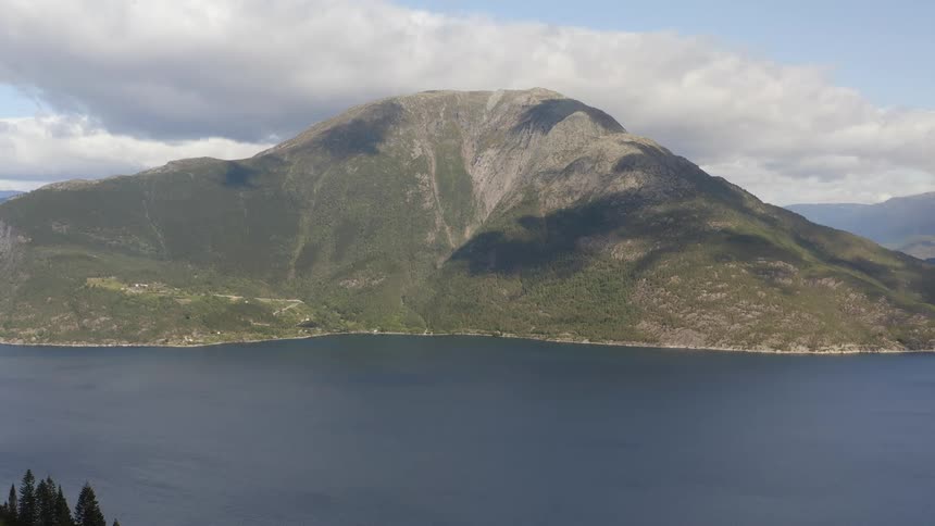 Aerial view of a mountain near a body of water is displayed
