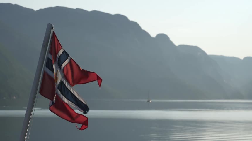 Flag flutters in the wind as fog obscures boat and nearby shore