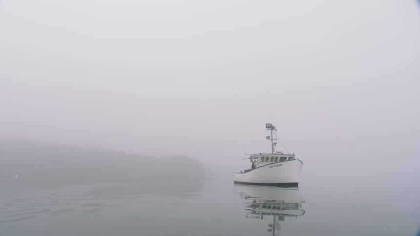 Fishing boat floating over the calm lake waters under the fog