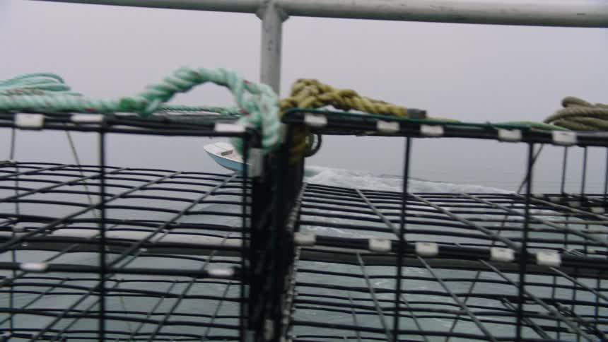 A man backs his boat away from fishing cages in a lake