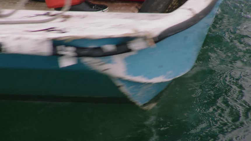 Person cranks boat motor and pilots it across water leaving a wake
