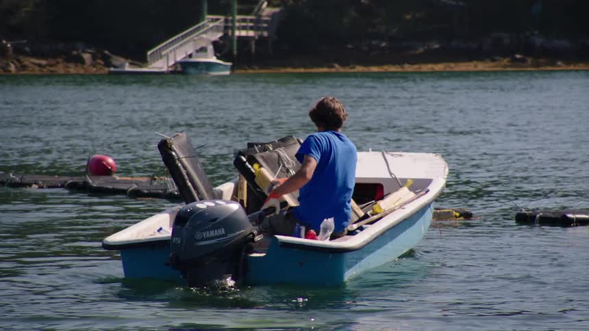 A man is starting his boat on a river at midday