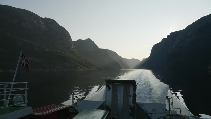 A ship sails in the water past the rocks