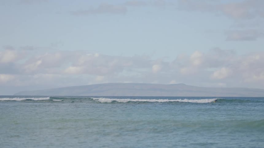 A person is surfing in the ocean at dusk