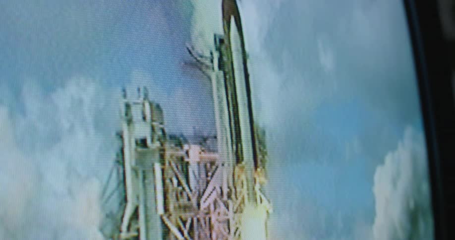Close up of a television screen showing vintage video of a space shuttle lifting off