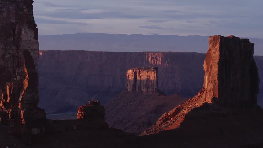 Shadows cover most of misty valley surrounded by plateaus and buttes