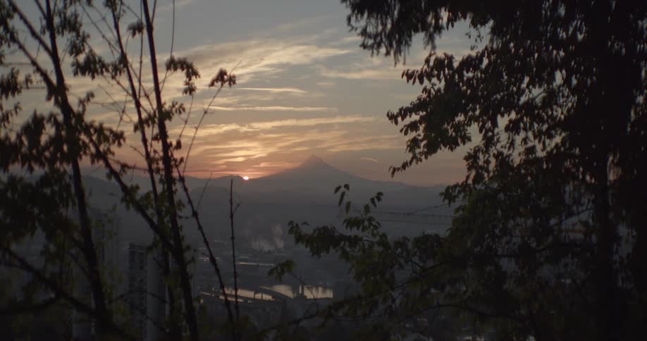 Time lapse of the sun rising over the mountains over a small city in the valley