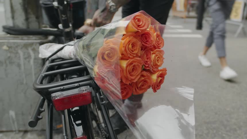 Young man unlocking a bicycle with a flower bouquet on the back