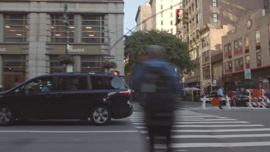 Pedestrians and traffic passes through downtown intersection with one side blocked by barriers