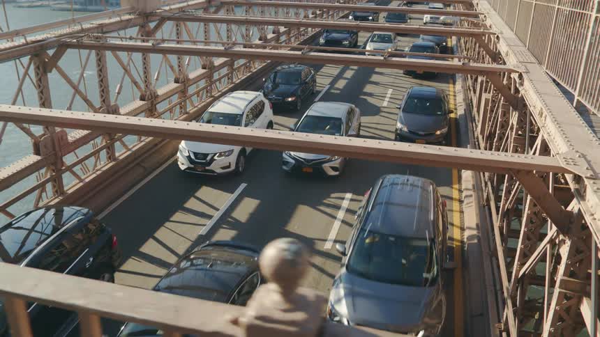 Cars are driving over a bridge near a downtown city
