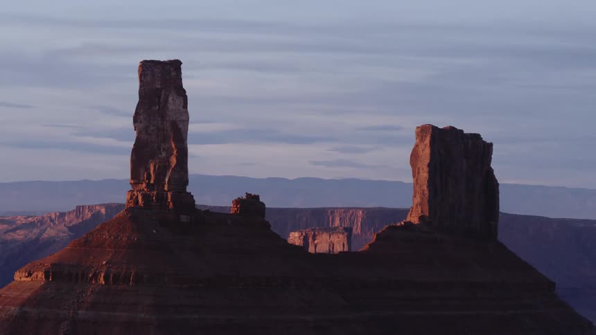 Aerial view of a tall rock tower over a mesa in the desert at sunset