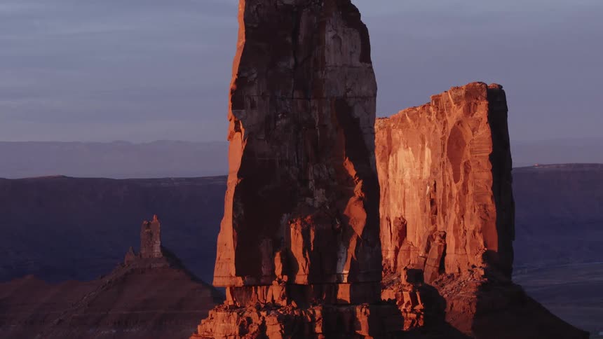 The sun shines on tall rock formations high in a hazy sky