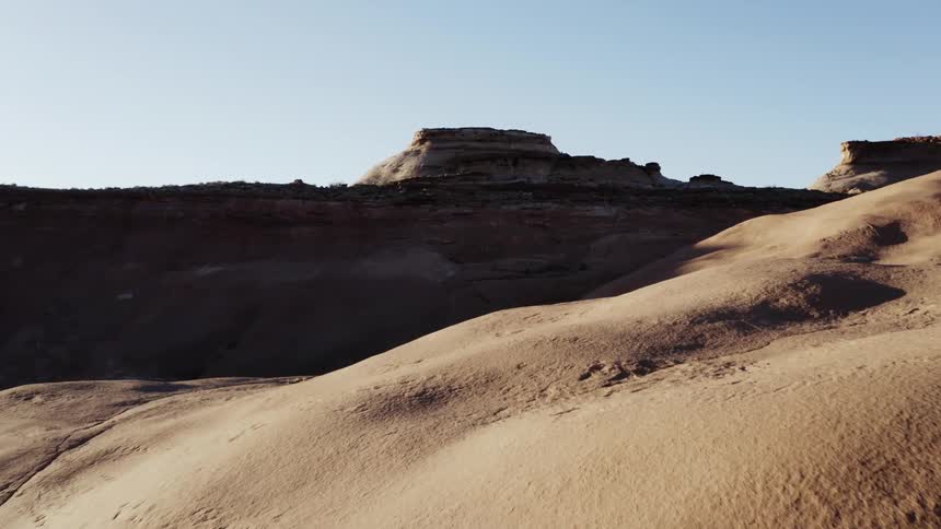 Arid hills leading to a mesa in desert on a clear day