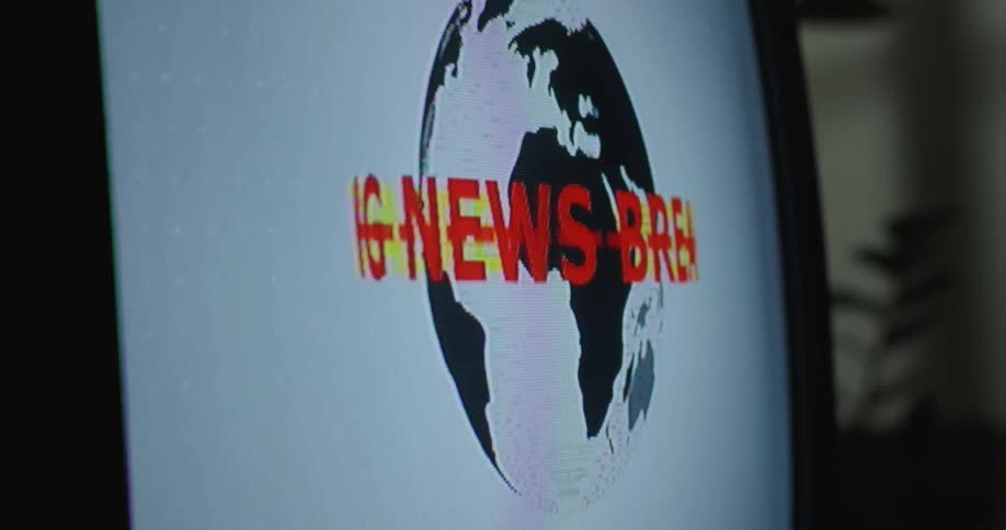 Close up of a television screen showing a rotating logo for breaking news