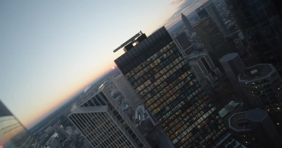 Light shines from lit rooms in skyscrapers with red tinted sky on the horizon