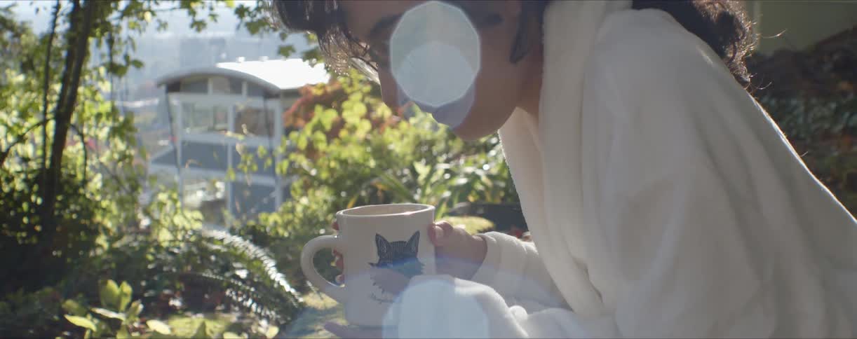 A woman is holding a mug in her yard