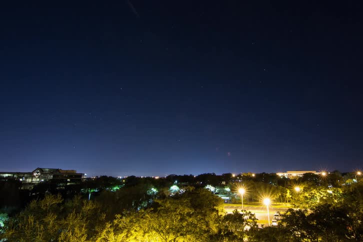 A bright meteor falls from the night sky into a neighborhood