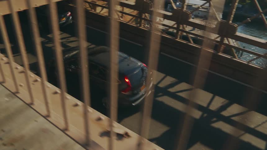 Cars travel on a bridge over a river while pedestrians walk above