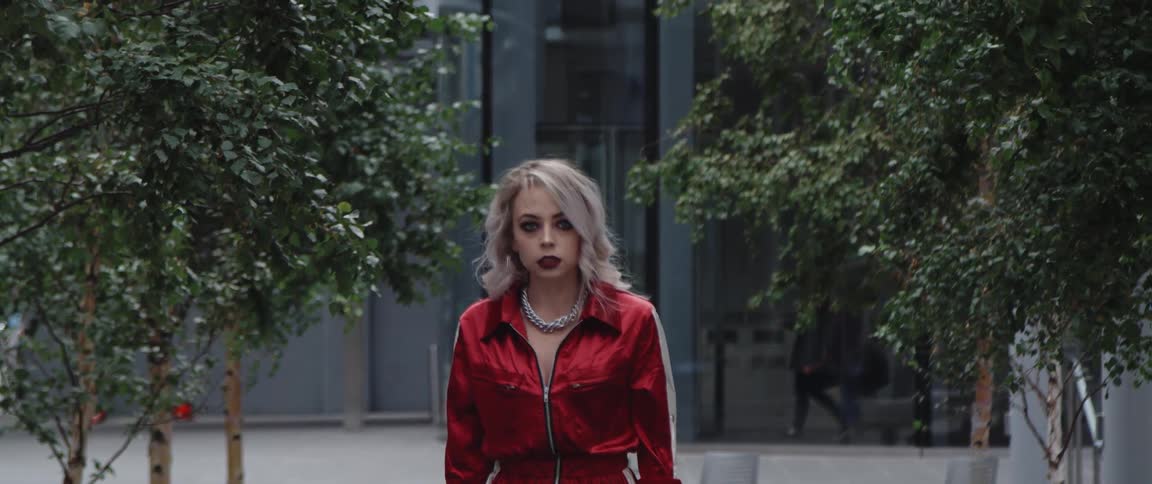 Model wearing red lipstick and a red outfit poses near building