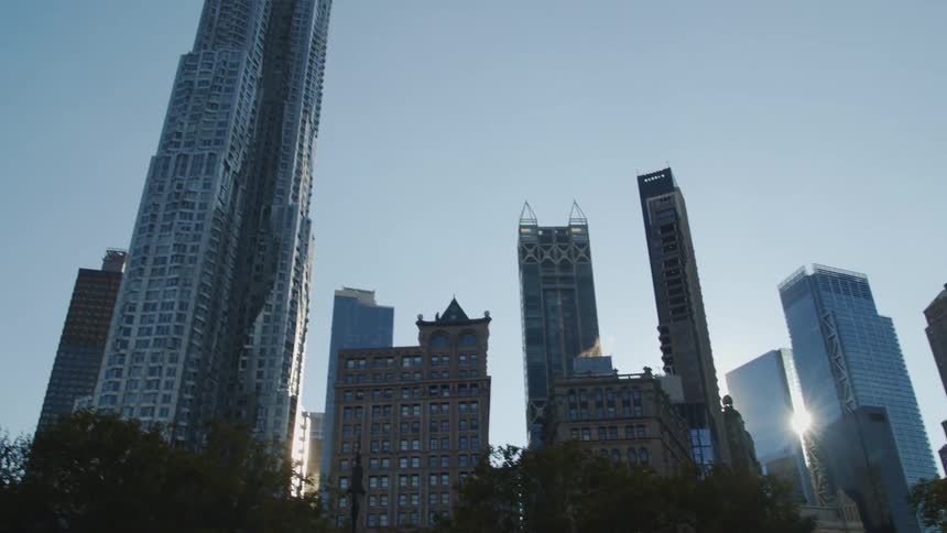 High rise office buildings wit sun shining between buildings at dusk