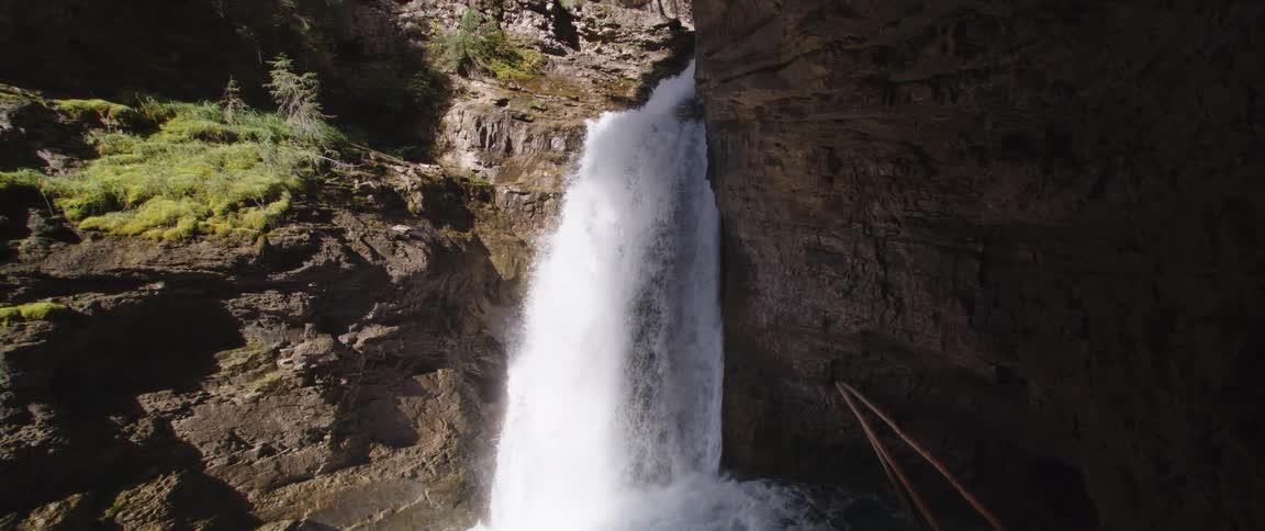 Waterfalls flowing down the side of a cliff into a stream below