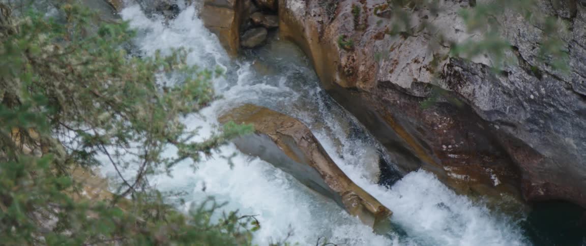 Turbulent water flowing in the river rapids through the rocks in the mountain