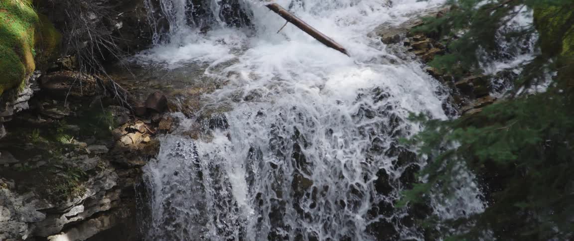 A waterfall off a cliff in the wilderness during the day