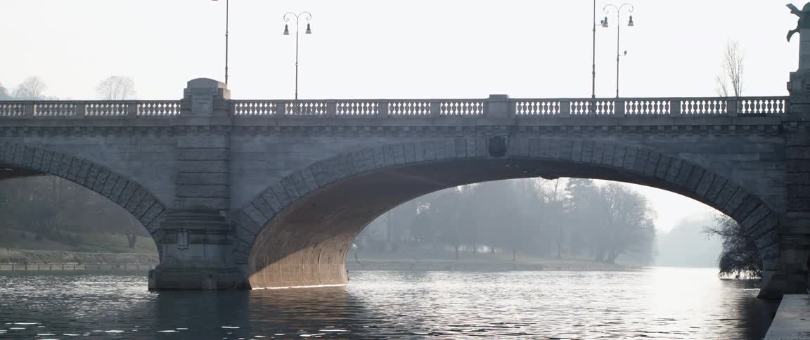 A large stone bridge over a river on a misty day
