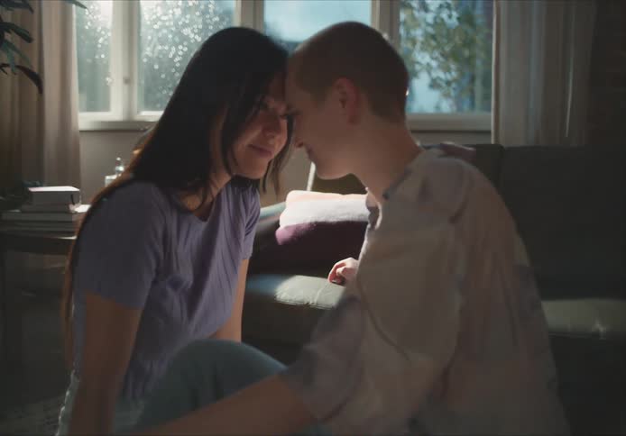 Two women lean forward to each other closely sitting on a floor