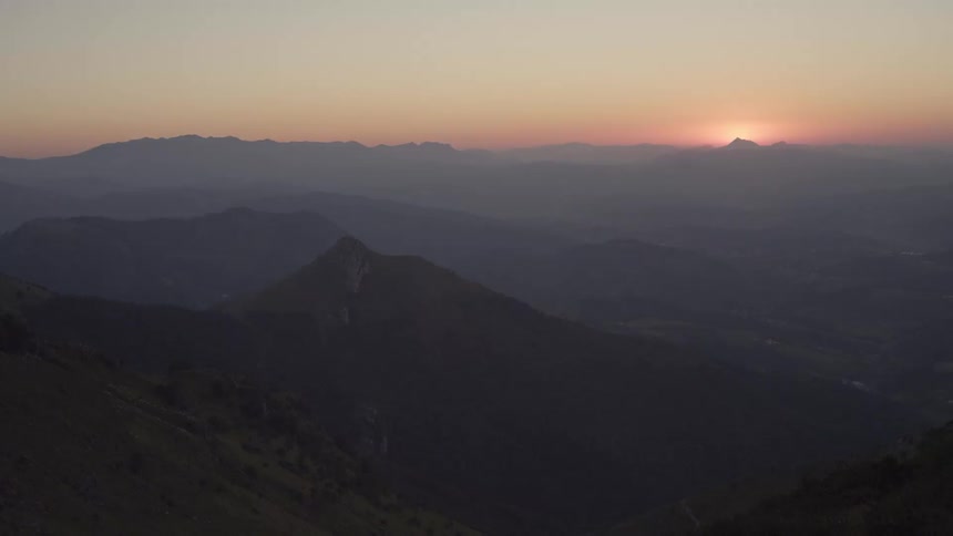 Mountain range in a hazy sky and the sun on the horizon