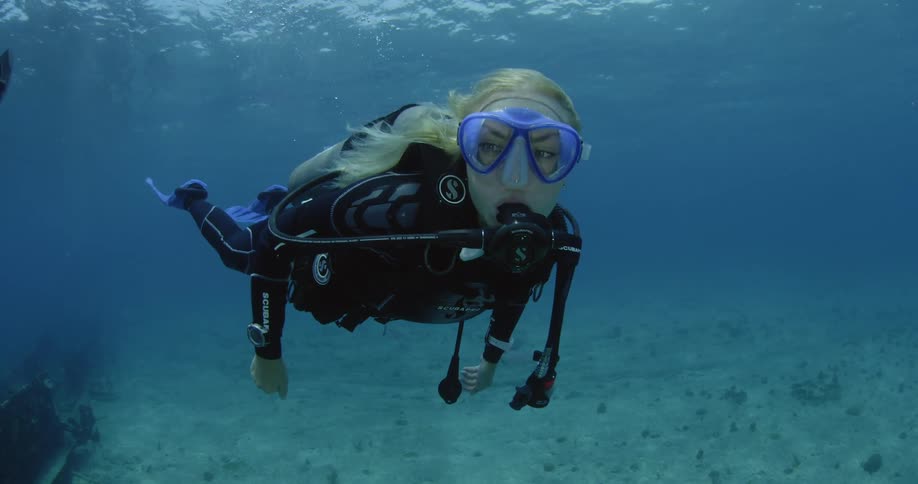 A female diver is traveling under the water looking around