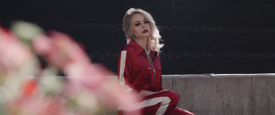 A woman is posing wearing a red track suit