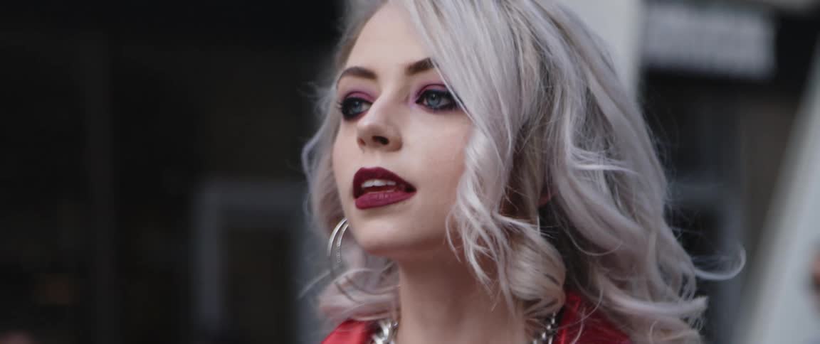 Woman with makeup hoop earrings necklace and red shirt walks down the street in the city